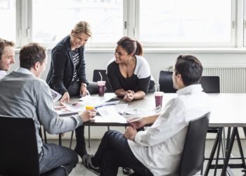 Group of business colleagues discussing at desk in office