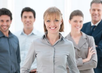 Happy smiling businesswoman standing with her colleagues at modern office