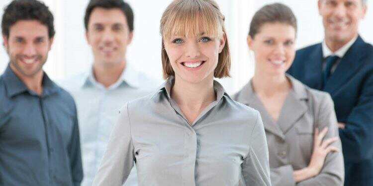 Happy smiling businesswoman standing with her colleagues at modern office