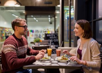 eating, vegetarian food and people concept - happy couple or friends having dinner at vegan restaurant