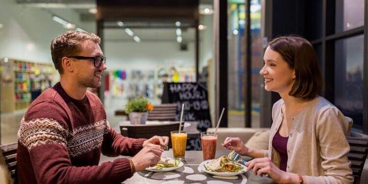 eating, vegetarian food and people concept - happy couple or friends having dinner at vegan restaurant