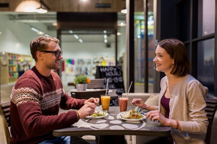 eating, vegetarian food and people concept - happy couple or friends having dinner at vegan restaurant