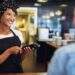 Smiling attractive African American small business owner taking payment from a customer processing a credit card through the handheld banking machine