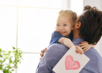 Happy father's day! Child daughter congratulating dad and giving him postcard. Daddy and girl smiling and hugging. Family holiday and togetherness.