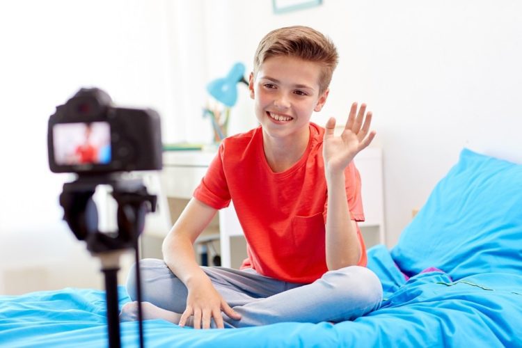 blogging, technology and people concept - happy smiling boy or blogger with camera recording video at home